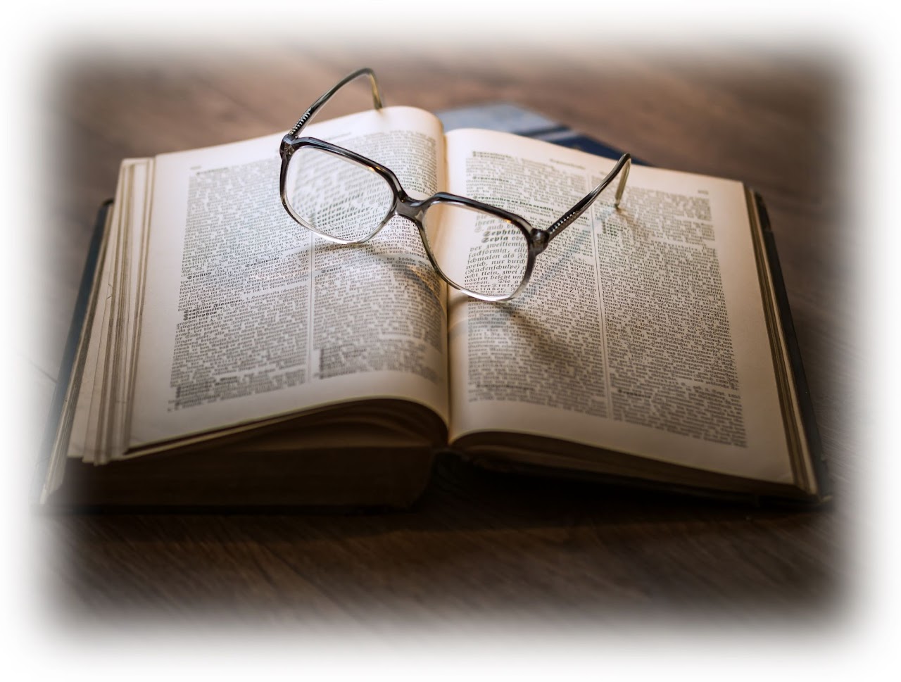 an open book with a spectacles on top